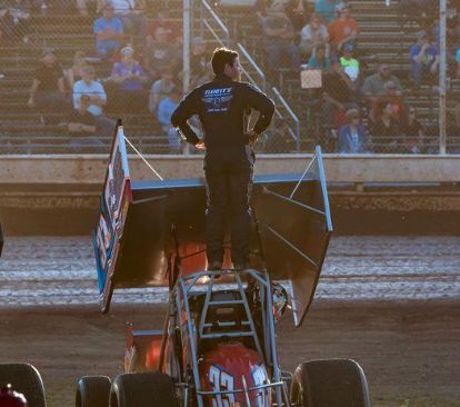 Cap Henry standing on top of his sprint car, saluting the grandstands